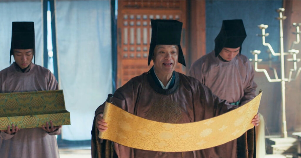 An imperial edict is being delivered by a eunuch