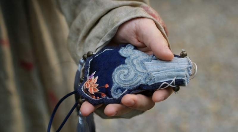 A scene from Chinese period drama, A Dream Within a Dream episode 4 recap of a hand holding a blue brocade pouch