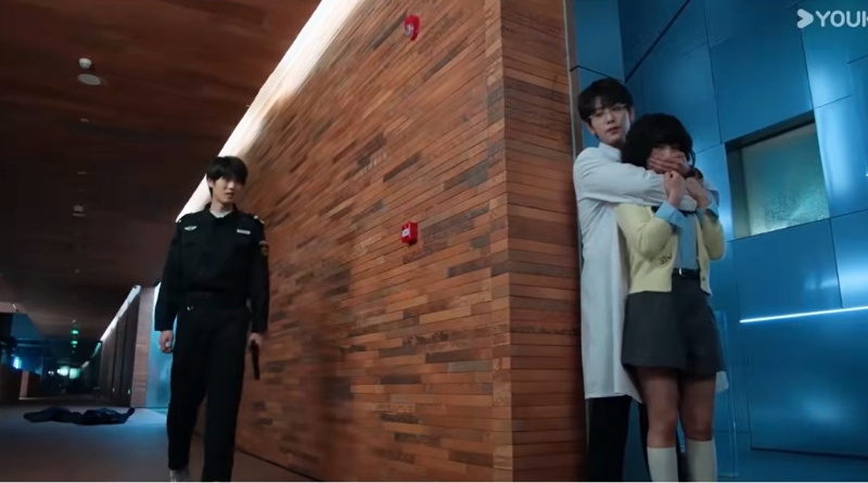 Affinity Episode 3 Recap: Chinese Drama scene of a doctor and and girl hiding around the corner from a man with a gun