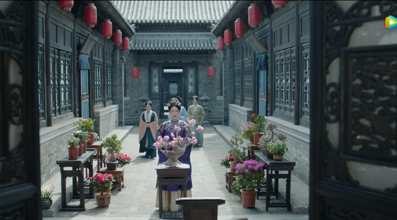 Scene from modern Chinese drama The Road To Splendor Episode 2 recap of woman in a concrete courtyard of potted flowers and plants