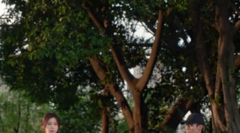 Scene from modern Chinese drama Road To Success of a woman handing snacks to a man on the grandstand with trees behind them