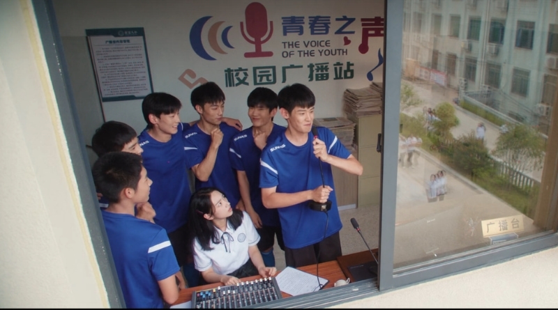 Scene from modern Chinese drama Road To Success Episodes 15-16 recap of 6 high school boys hijacking the a school radio making an announcement, with a female student watching them in anger