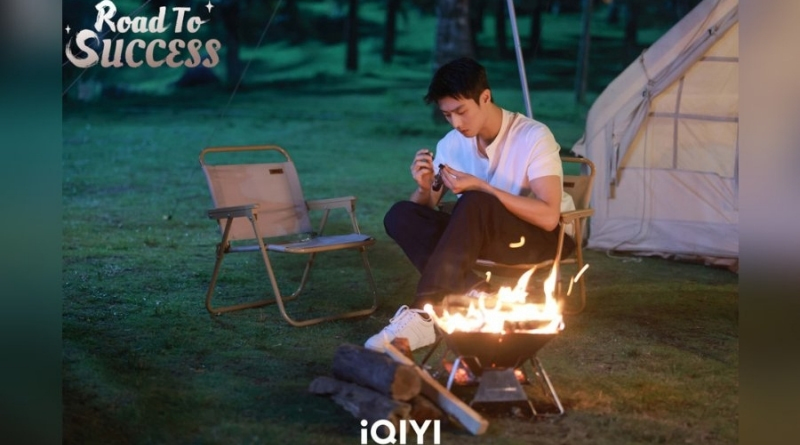 Scene from modern Chinese drama Road To Success Episodes 17-18 recap a man fixing a watch in front of a fire pit while camping