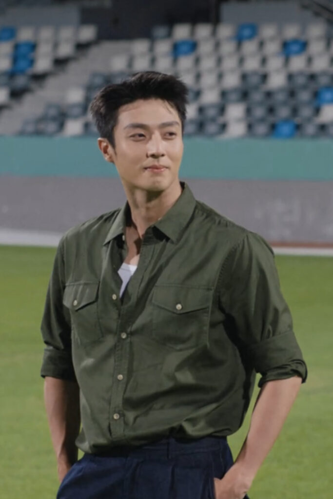Scene from modern Chinese drama Road To Success Episodes 31-32 recap a man in a green shirt, smiling while standing in a stadium