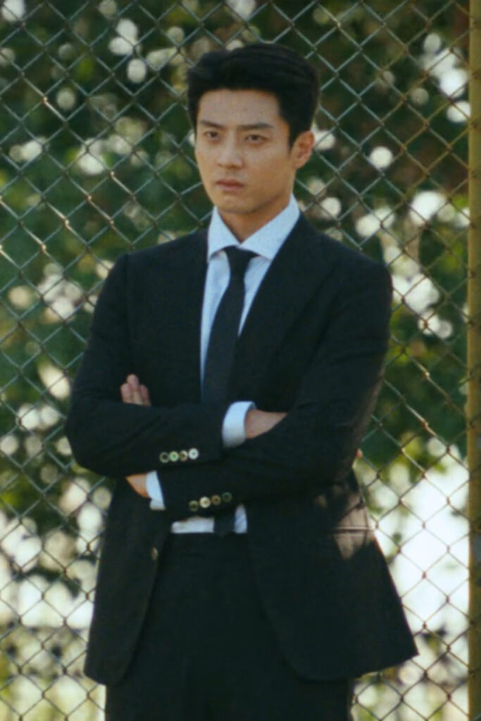 Scene from modern Chinese drama Road To Success episodes 9-10 recap of a man in a black suit with his armed crossed, looking stern
