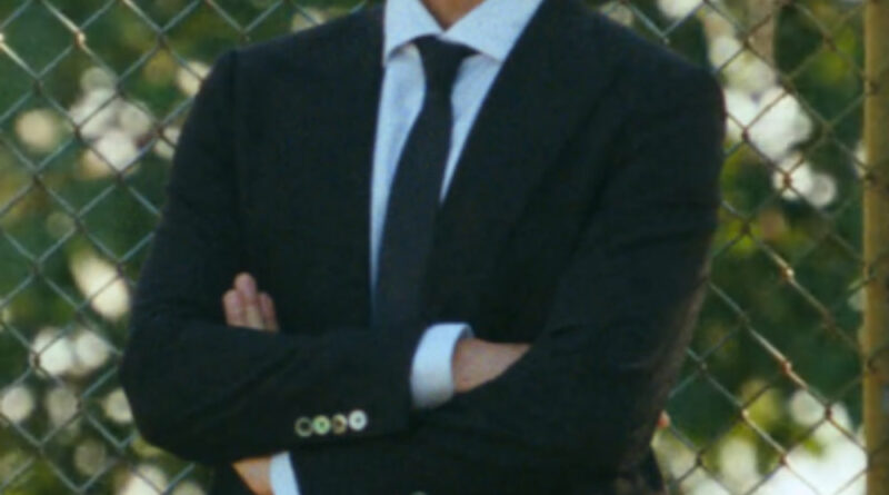 Scene from modern Chinese drama Road To Success episodes 9-10 recap of a man in a black suit with his armed crossed, looking stern