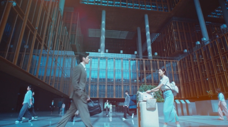 Scene from modern Chinese drama The Early Spring Episode 1 recap and review of a man and a woman with suit case passing each other in a lobby of a building