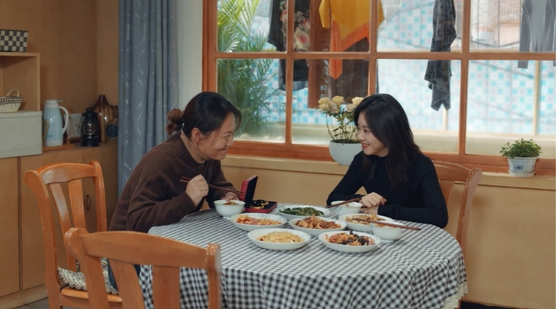 Scene from modern Chinese drama Road Home Episode 15 recap and review of 2 women smiling at each other in conversation at dinner