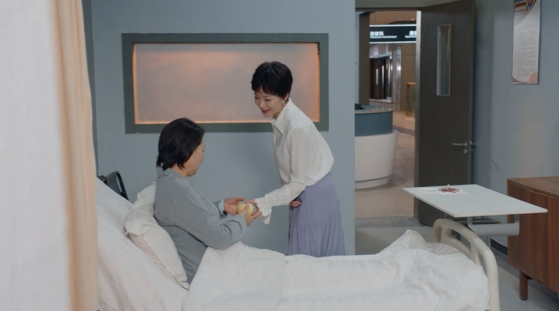 Scene from modern Chinese drama Road Home Episode 24 recap and review of a woman handing cut fruit to her friend in the hospital