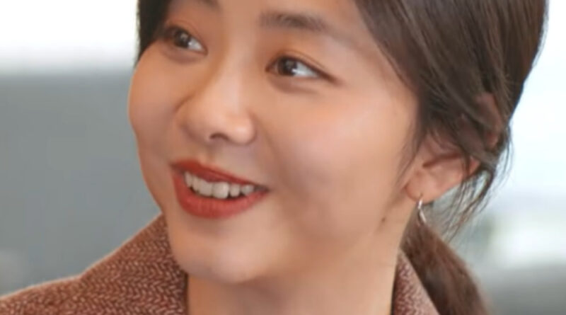 Scene from modern Chinese drama Road Home Episode 7 recap and review of a woman smiling and wearing a brown coat