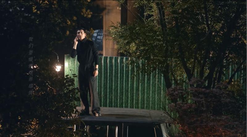 Scene from modern Chinese drama Road Home Episode 9 recap and review of a man on the phone, standing on top of his car