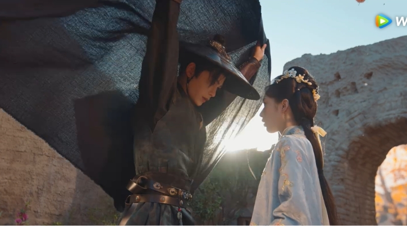 A scene from The Road To Splendor Romance Review and Recap (2026) of a man sheltering a woman with his cape