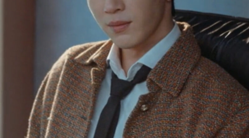 Scene from modern Chinese drama The Early Spring Episode 6 recap and review of a man sitting in his office chair, thinking, wearing a brown jacket and black tie
