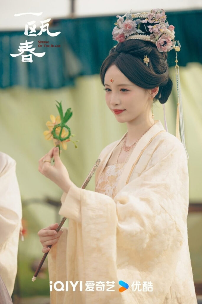 Scene from period Chinese drama Spring of The Blade (2026) Episode 5 Recap and review of a woman in yellow hanfu holding an orchid knot